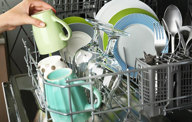 a women emptying clean glasses and dishes from the dishwasher